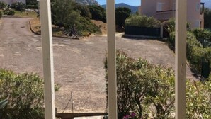 A residential area with a paved driveway, a building with a red roof, and a mountain in the background. - Apartment 'La Terrazza Sulla Baia Di Calvi' with Sea View, Private Terrace and Private Garden (Lumio)