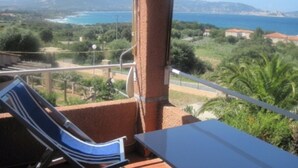 A balcony with a view of the sea and mountains, a chair, and a table. - Apartment 'La Terrazza Sulla Baia Di Calvi' with Sea View, Private Terrace and Private Garden (Lumio)