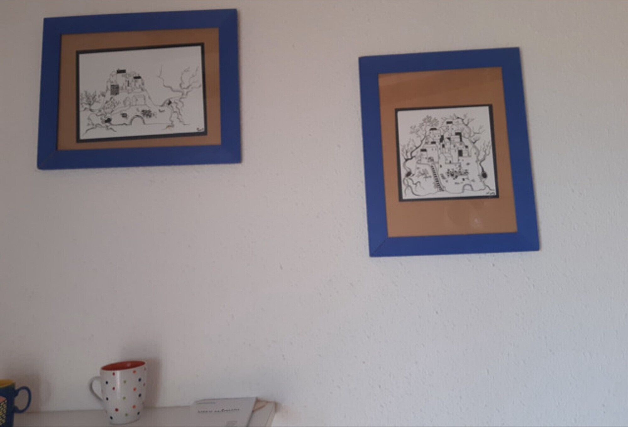 Zwei gerahmte Schwarz-Weiß-Zeichnungen an einer Wand.