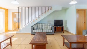 Una sala de estar con escaleras, un sofá, un televisor y muebles de madera.