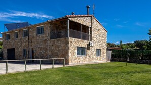 Un edificio de piedra con balcón, garaje y panel solar.