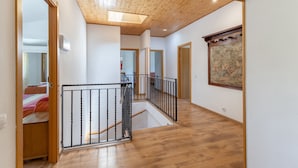 Un pasillo con suelo de madera, una escalera y una obra de arte enmarcada en la pared.