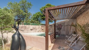 Ein Wellnessbereich mit Whirlpool, Liegestühlen und einer Pergola.