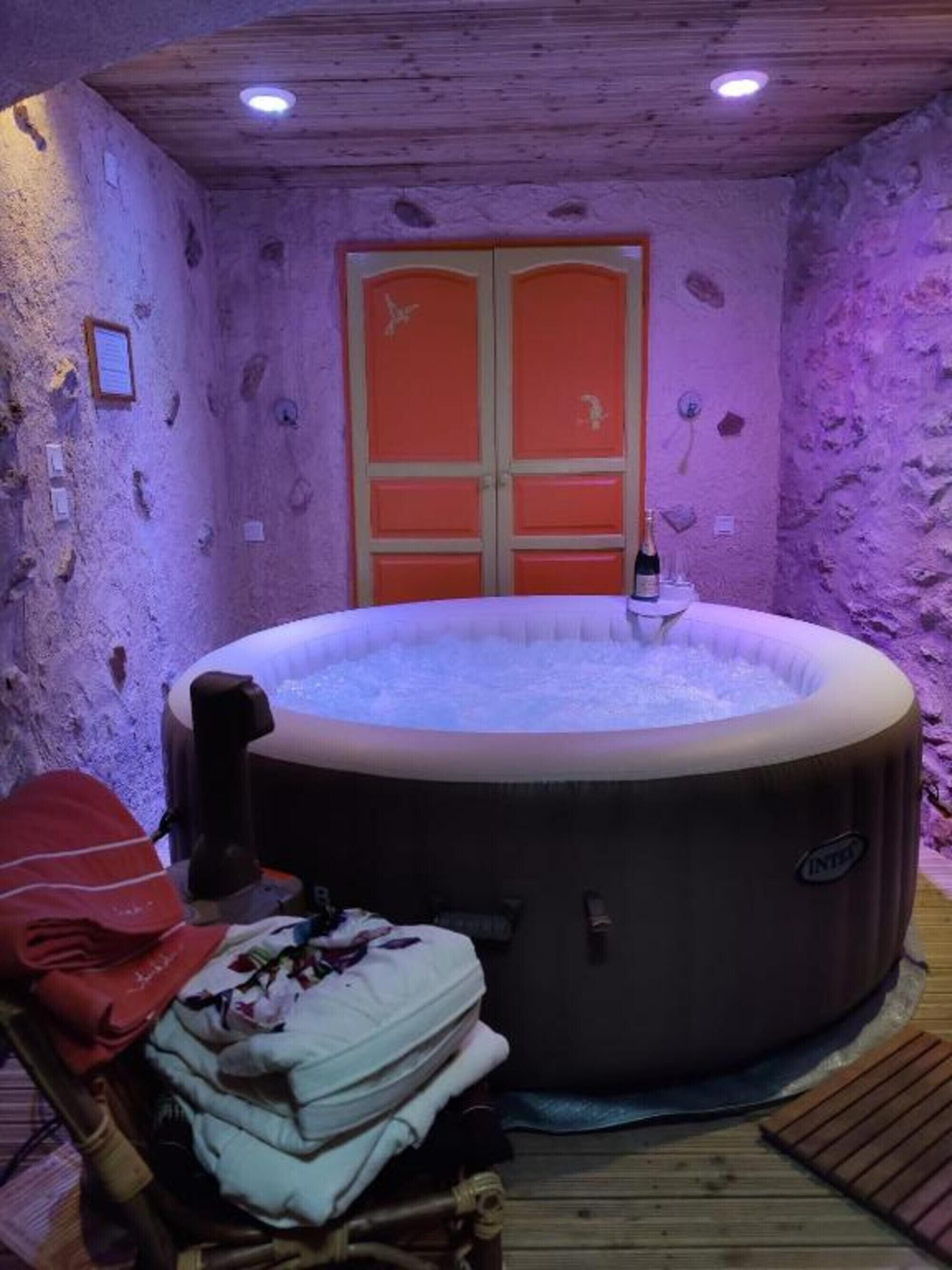 Een hottub in een ruimte met stenen muren, een houten plafond en een paar rode deuren.