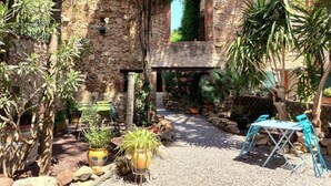 Ein Innenhof mit Steinmauern, Blumentöpfen und Gartenmöbeln.