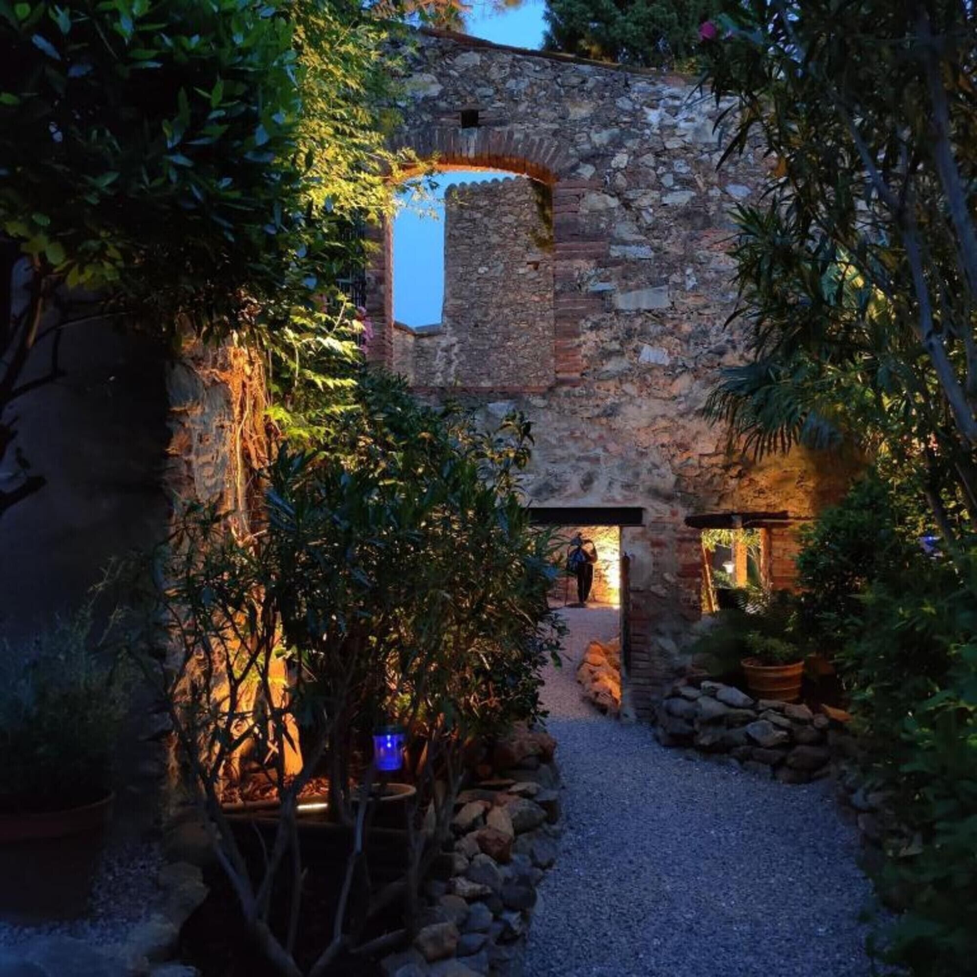 An outdoor stone building with a narrow pathway leading to a door.