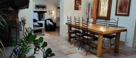 Un coin repas avec une table et des chaises en bois, une cheminée et une vue sur le salon.