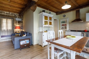 Una sala de estar acogedora con un sofá, una mesa de comedor de madera, un armario blanco y una zona de cocina con alacenas y una estufa.