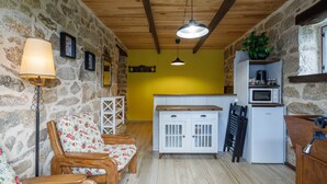 Una cocina rústica con paredes de piedra, muebles de madera y un armario blanco.