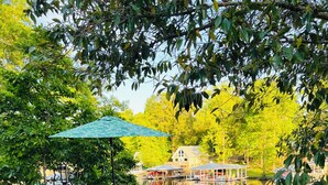 A wooden deck with outdoor furniture, a table with a potted plant, and a view of a lake with boats. - Cozy, comfortable Lakehouse getaway - Sleeps 10! WiFi, Private Dock (Cordele)