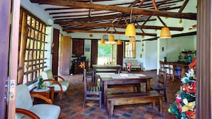 A rustic dining area with wooden furniture, a tiled floor, and a wooden ceiling structure. - Sueño Real Campestre Hostel (Pinchote)