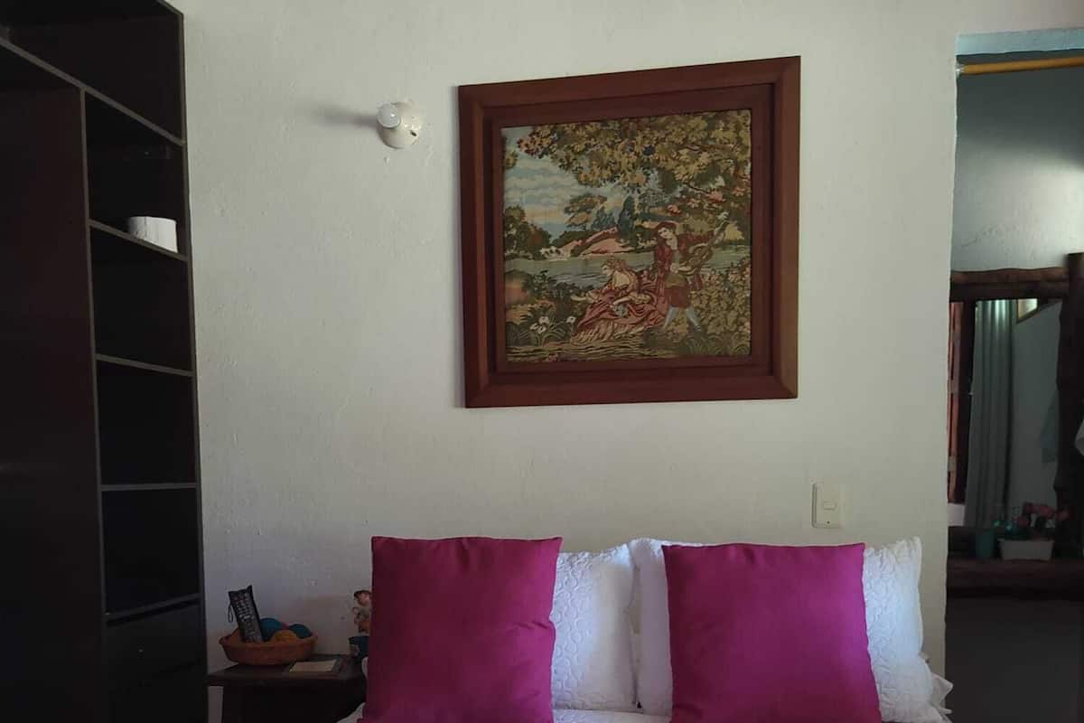 Une chambre à coucher avec un lit, deux oreillers, une table de chevet, un tableau et une armoire.