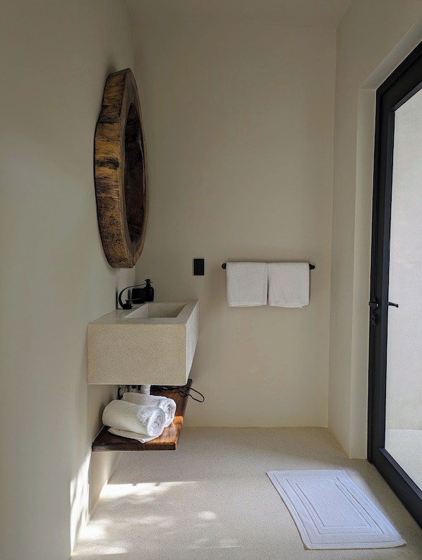 A bathroom with a large mirror, a sink, and a towel rack. - Punta Mágica (Puerto Escondido)