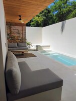 Un espacio exterior moderno con piscina, sofá y ventilador de techo.