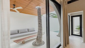 A modern interior with a glass door leading to a pool area, a wooden ceiling, and a bench. - Punta Mágica (Puerto Escondido)