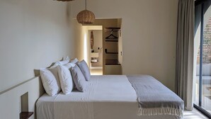 A modern bedroom with a bed, hanging wicker lamps, a ceiling fan, and a view of the outside. - Punta Mágica (Puerto Escondido)
