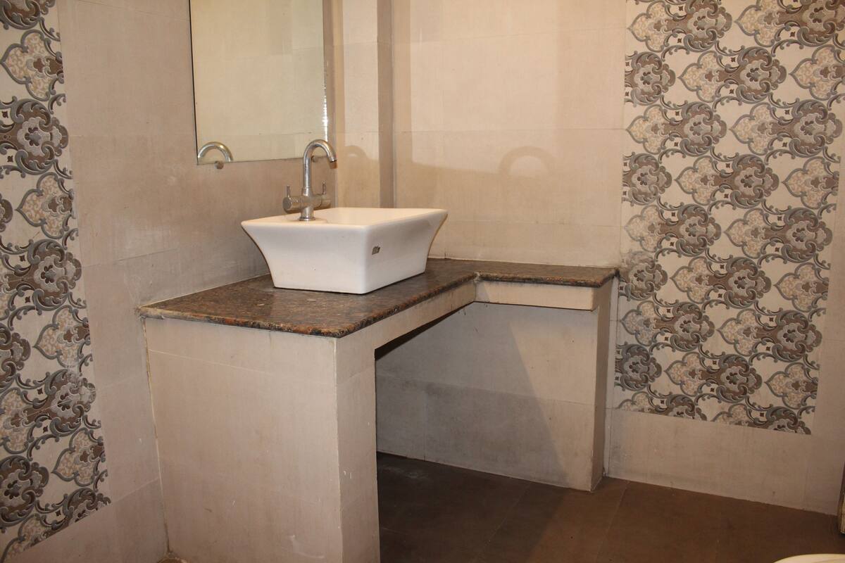 A bathroom with a white sink, a mirror, and patterned tiles on the walls.