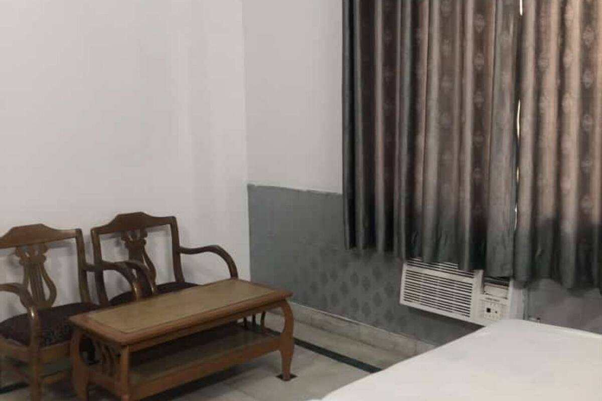A room with a wooden bench, two chairs, a bed, and a radiator.