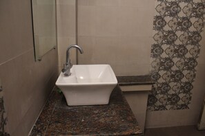 A bathroom with a white sink, a mirror, and patterned tiles. - Shree Chitra Residency by Avadhesh Grou (Haridwar)