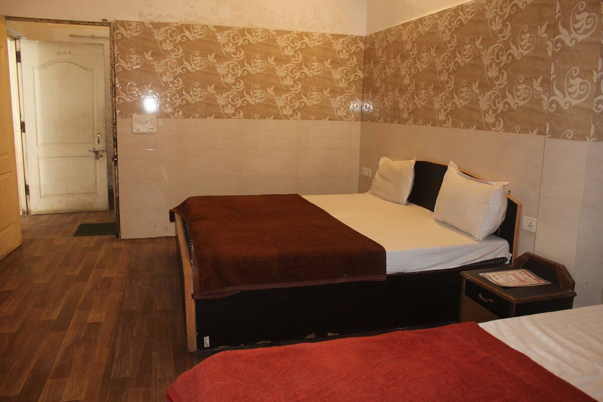 A hotel room with a bed, a nightstand, and a door.