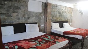 Two single beds with wooden frames and headboards, a stone wall, and a tiled floor. - Shree Chitra Residency by Avadhesh Grou (Haridwar)