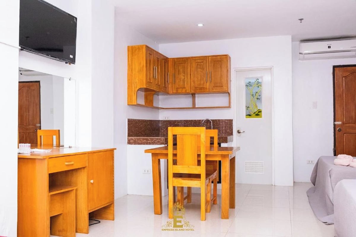 A compact hotel room with a kitchenette, a dining area, and a bed.
