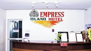 Una reception dell'Hotel Empress Island con un logo, un cartello che indica divieto di fumo e alcuni documenti incorniciati.
