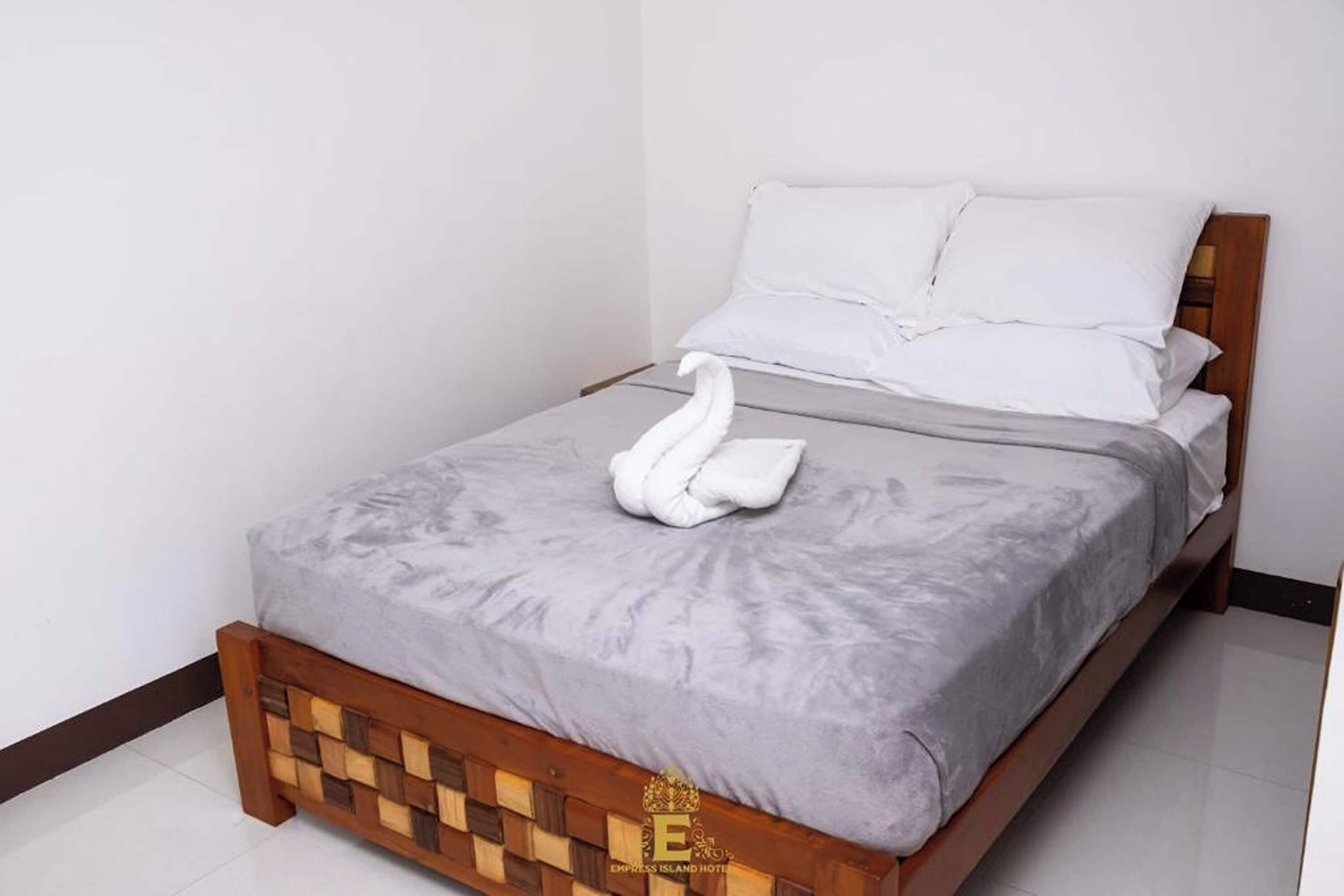 A neatly made bed with a grey bedspread and two white pillows.