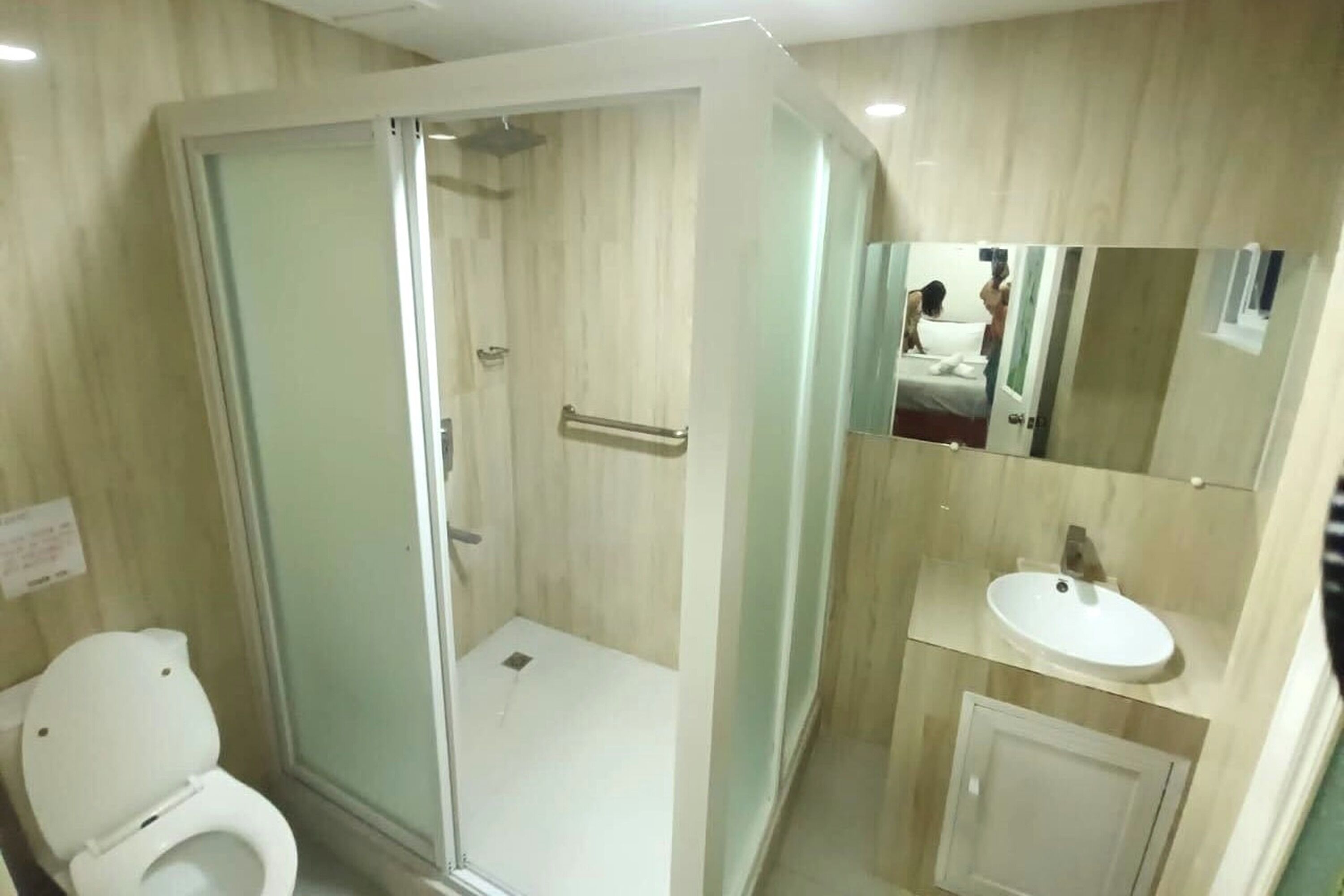 Une salle de bain avec une douche à parois de verre, des toilettes et un lavabo avec un miroir au-dessus.