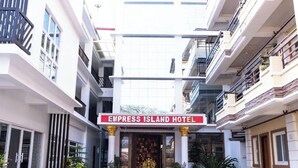 L'ingresso dell'Hotel Empress Island, con un cartello rosso, colonne e piante in vaso.