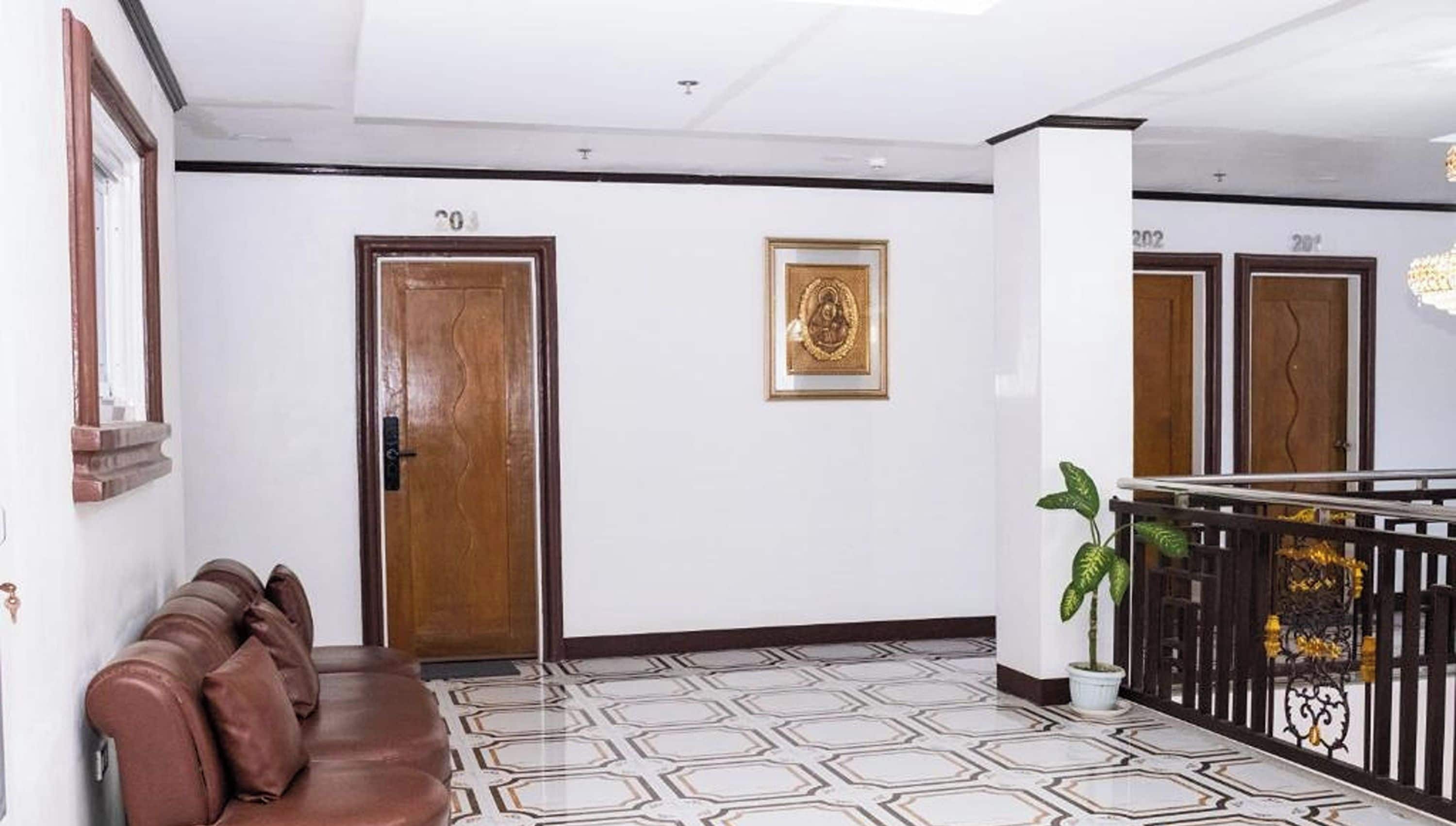 A hotel lobby with a brown leather sofa, a wooden door, and a framed picture on the wall.