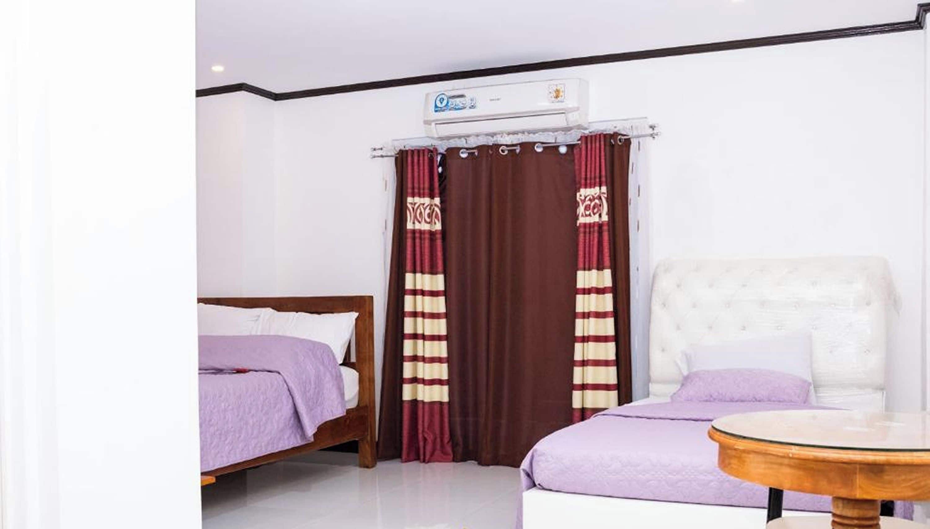 Une chambre d’hôtel avec deux lits, une table ronde et un ventilateur de plafond.