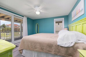 A bedroom with a bed, a ceiling fan, a window, and a view of the outside.
