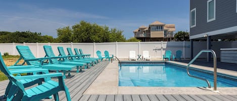 Área de piscina com várias espreguiçadeiras azuis e uma piscina pequena.