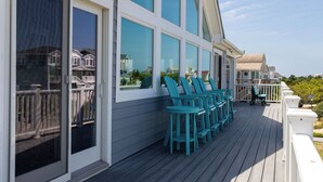 A wooden deck with turquoise chairs and a white railing. - A Golden Opportunity: Semi-Oceanfront w/Heated Pool, Hot Tub and Across from Beach! (Corolla)