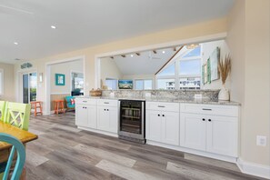 A spacious kitchen with white cabinets, a built-in oven, and a large window overlooking a residential area. - A Golden Opportunity: Semi-Oceanfront w/Heated Pool, Hot Tub and Across from Beach! (Corolla)