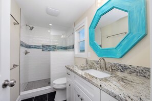 A bathroom with a shower, toilet, and sink.