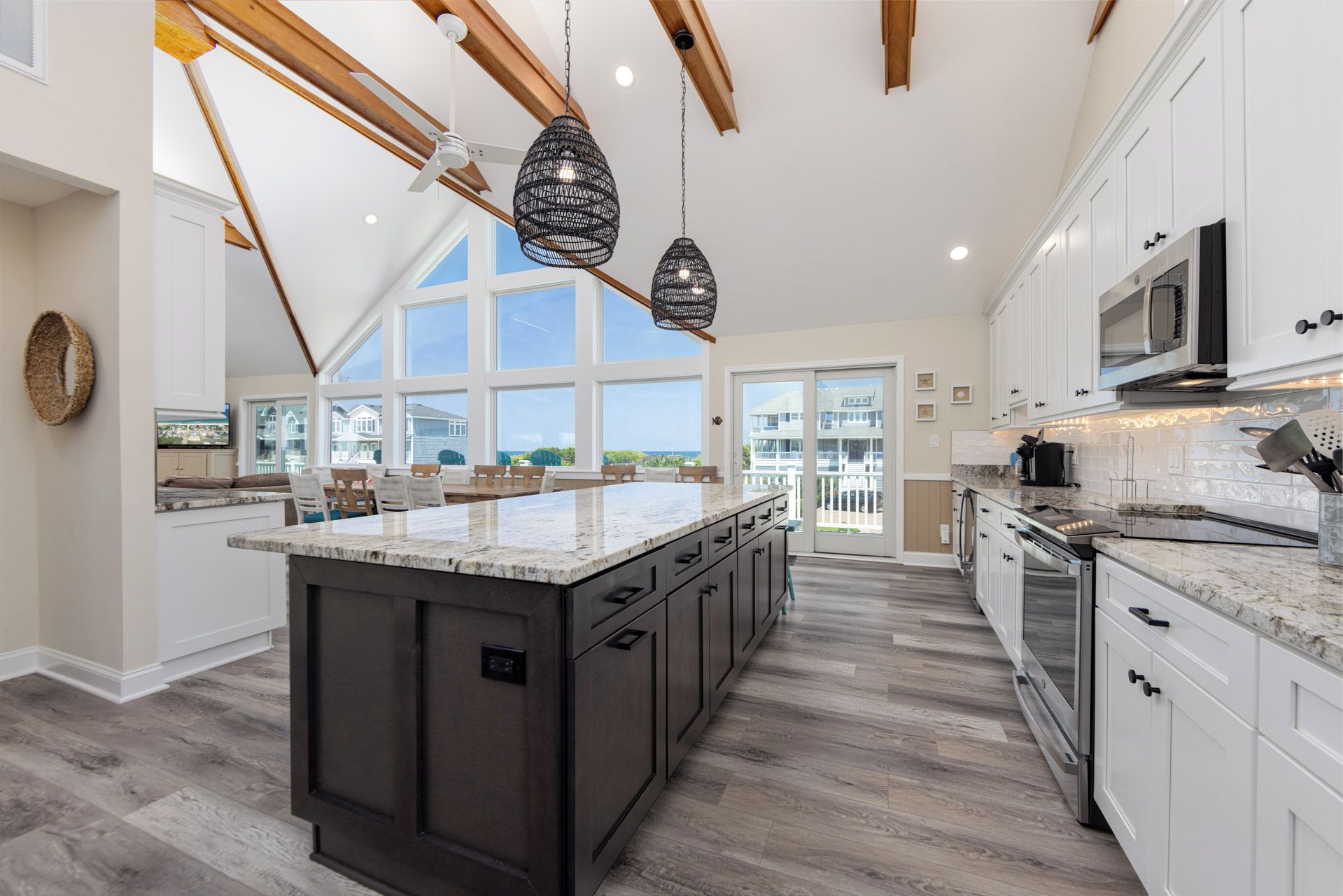 A spacious kitchen with a large island, dark cabinetry, and a view to the outside.