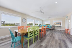A spacious room with a dining table and chairs, a sofa, and a ceiling fan. - A Golden Opportunity: Semi-Oceanfront w/Heated Pool, Hot Tub and Across from Beach! (Corolla)