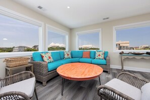 A sunlit patio with a teal sectional sofa, wicker chairs, and a round orange table. - A Golden Opportunity: Semi-Oceanfront w/Heated Pool, Hot Tub and Across from Beach! (Corolla)