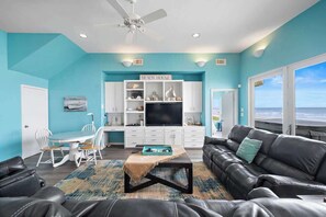 A living room with a TV, white cabinets, a sofa, and a dining area.