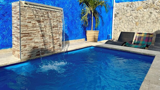 A swimming pool with a stone wall and a blue textured wall. - Casa Stephanie- Prívate Pool (Cartagena de Indias)