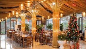 A spacious dining area with long tables and chairs, a large Christmas tree, and a modern ceiling design.