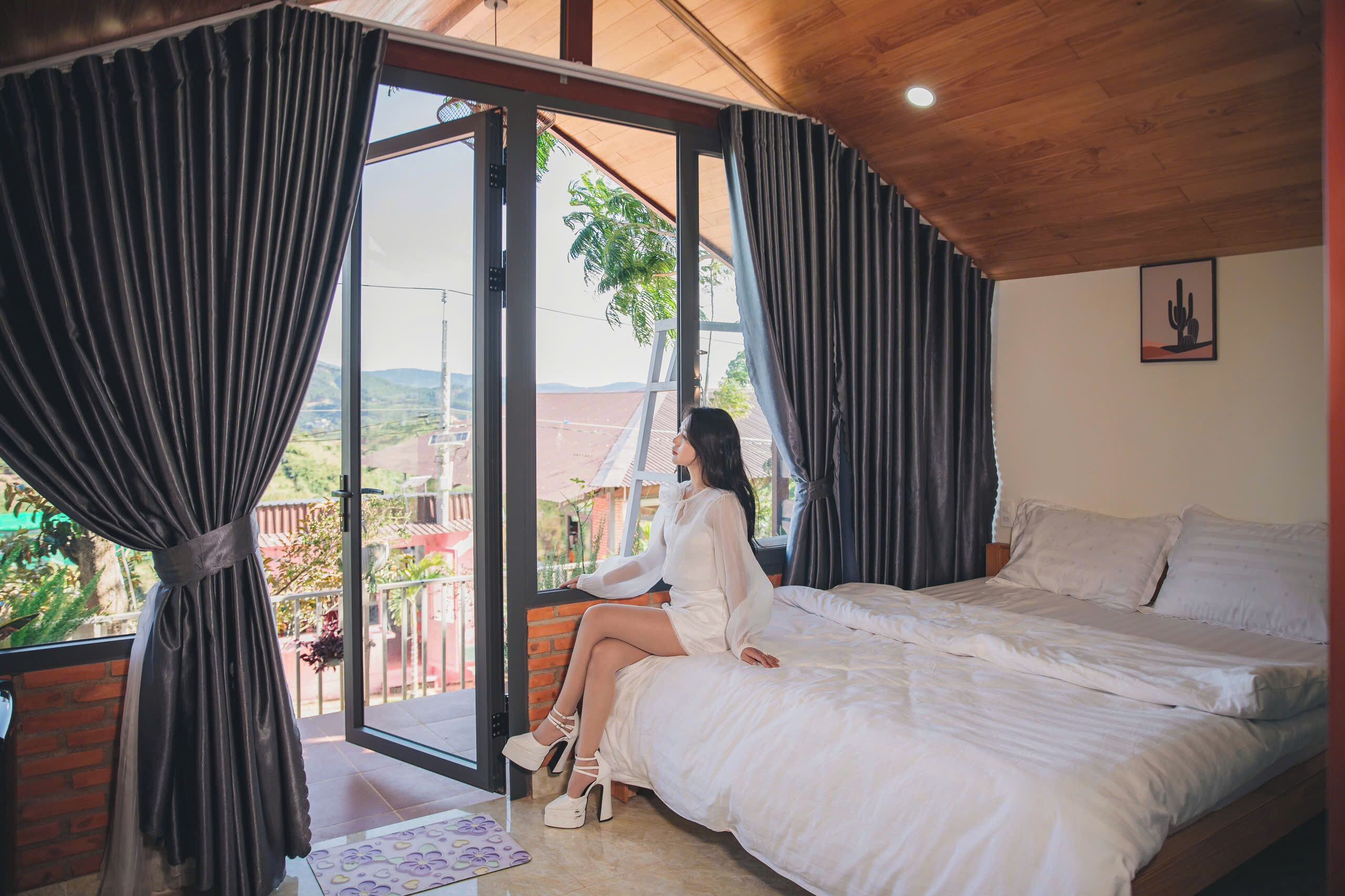 A bedroom with a large bed, a view of the outdoors, and a balcony.