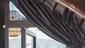 A room with a large window offering a view of green hills.