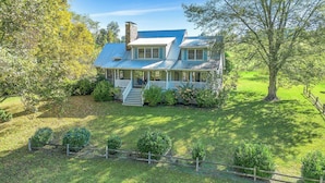 A large house with a porch, surrounded by a well-maintained lawn and trees.