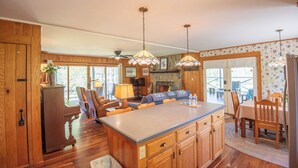A spacious kitchen with wooden cabinets, a central island, and pendant lighting.