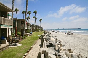 A beachfront hotel with a pool area, palm trees, and a view of the ocean and pier.