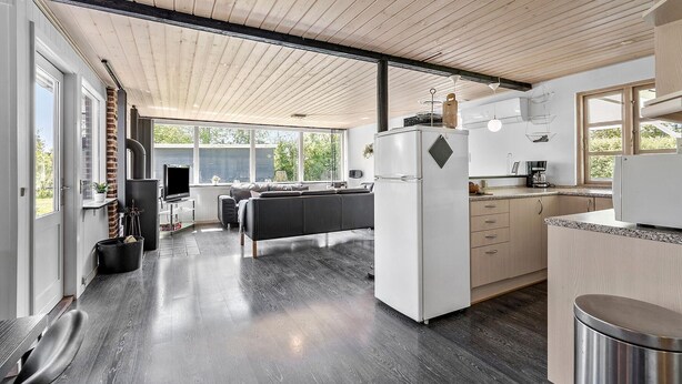 A modern kitchen with a central island, built-in appliances, and large windows offering views of the outdoors. - Stunning home in Tarm with kitchen (Tarm)