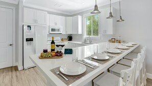 A modern kitchen with white cabinetry, a central island with a dining setup, and a built-in microwave. - Isla Key Acaí: Waterfront Boutique Resort, FREE Boat Dockage Sep-Oct Only! (Islamorada)